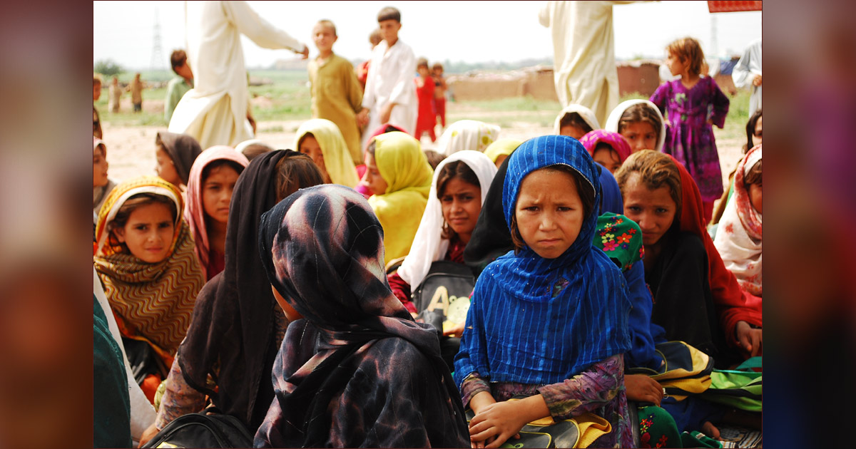 Several children are gathered with a few adults in the background. Several children are gathered with a few adults in the background.