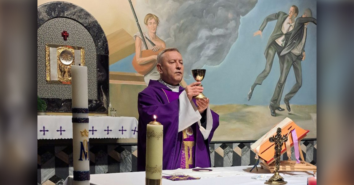 The priest Anatol Parakhnevich is raising a communion cup.