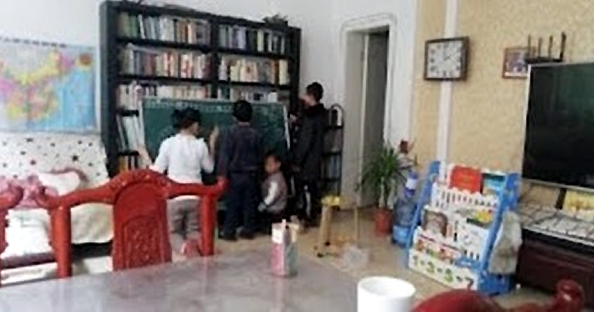 Three adults and a child using a chalkboard in the corner of a room. Three adults and a child using a chalkboard in the corner of a room.