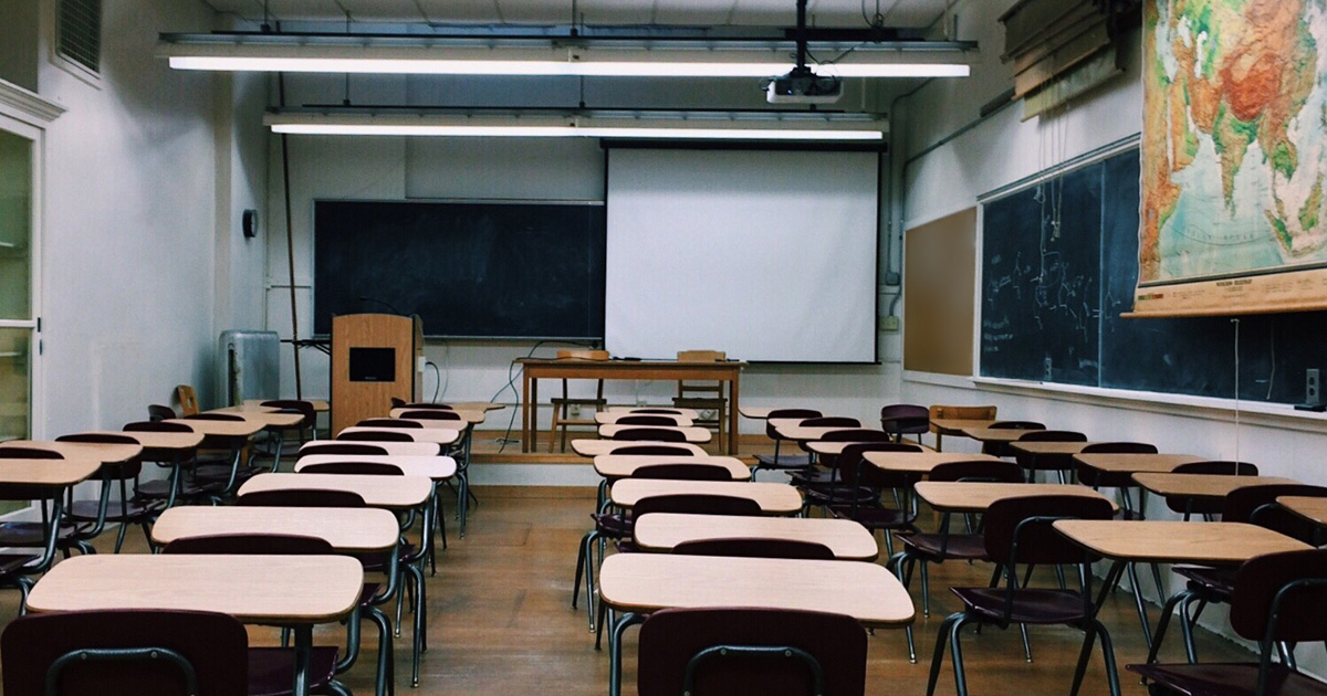 A classroom is full of empty desks, some chalkboards, and a map of Asia. A classroom is full of empty desks, some chalkboards, and a map of Asia.