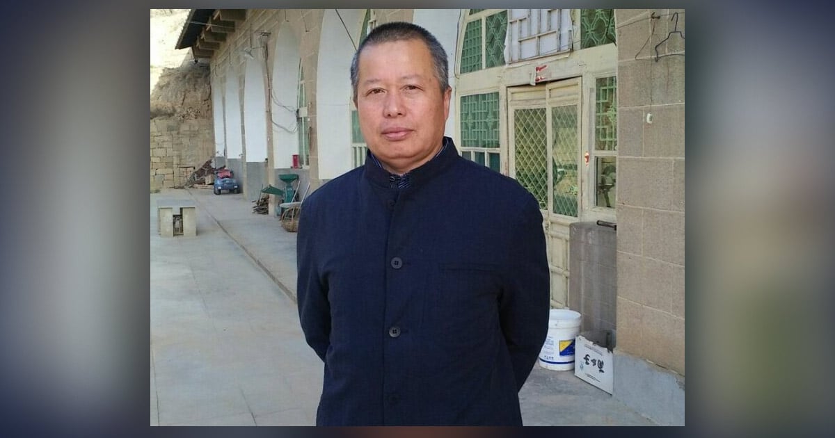 Gao Zhisheng is standing in front of a building dressed in a dark blue jacket.