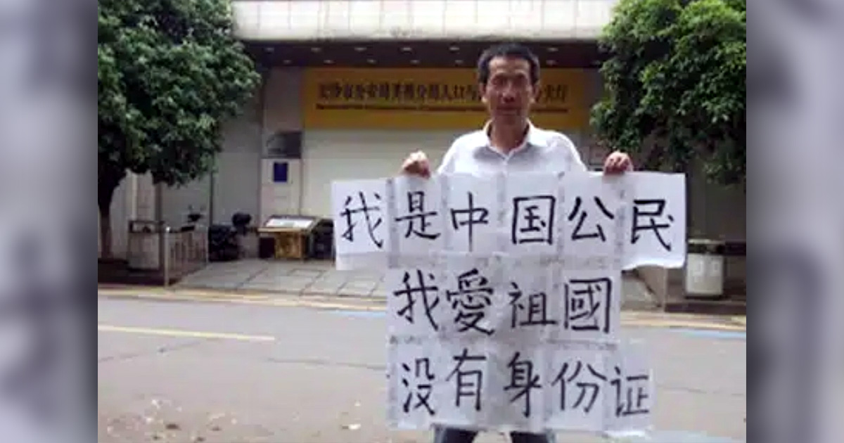 John Cao is holding up a sign with Chinese lettering. John Cao is holding up a sign with Chinese lettering.