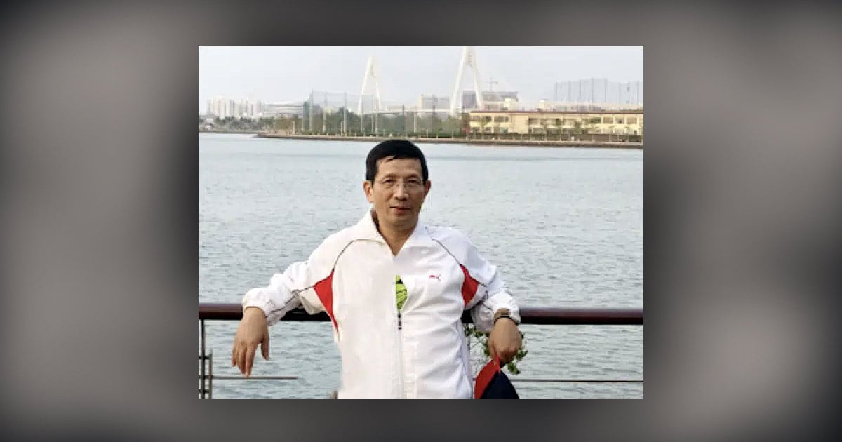 Pastor John Cao is leaning against a railing with water behind him.