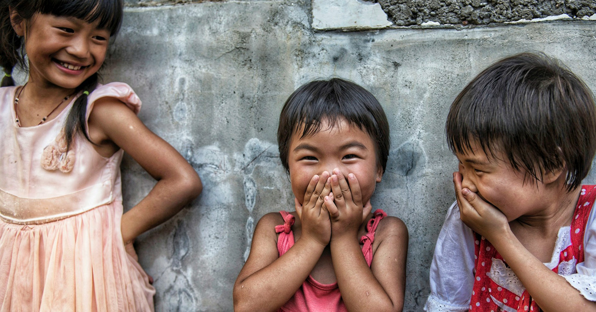 Three children are laughing together.