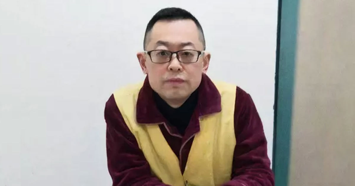 Photograph of Pastor Wang Yi seated indoors, wearing a burgundy shirt and yellow safety vest. A plain light wall and teal doorframe form the background. Photograph of Pastor Wang Yi seated indoors, wearing a burgundy shirt and yellow safety vest. A plain light wall and teal doorframe form the background.