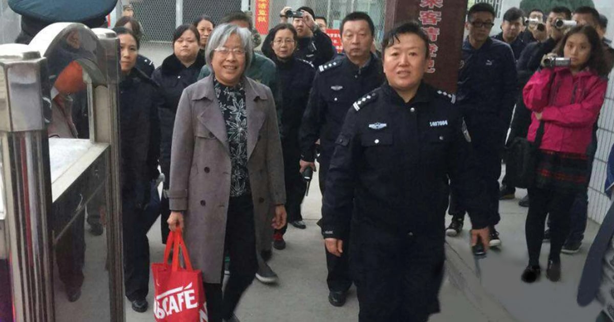 Yang Rongli is smiling. She is surrounded by group of people, many of whom are holding cameras.