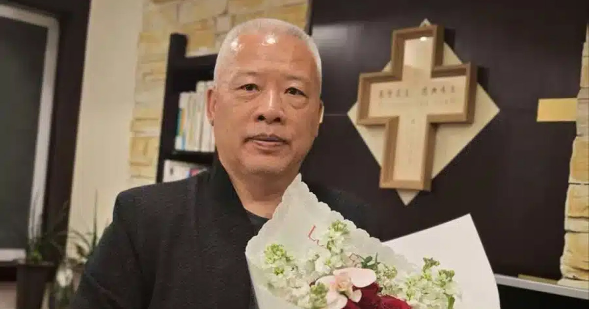 Elder Zhang Chunlei is holding a large bundle of flowers. There is a cross on the wall behind him. Elder Zhang Chunlei is holding a large bundle of flowers. There is a cross on the wall behind him.