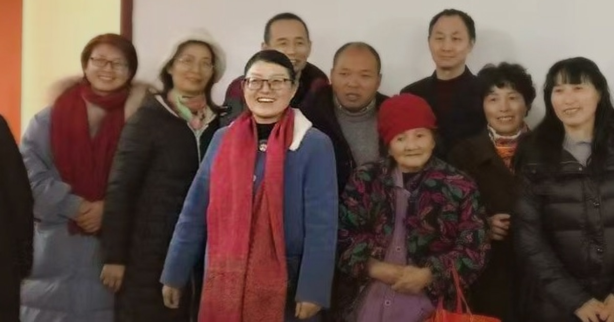 Zhang Mei is smiling. She is surrounded by others who also look happy. Zhang Mei is smiling. She is surrounded by others who also look happy.