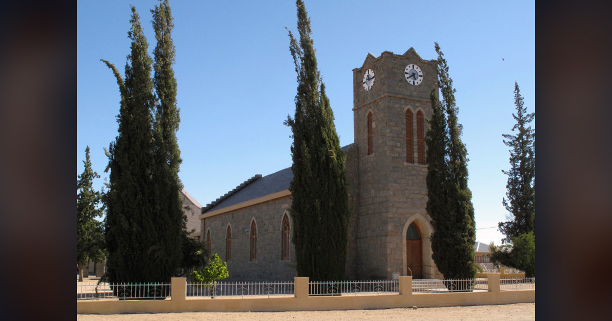 A church building is surrounded by tall trees.