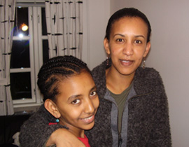 Helen Berhane and her daughter are smiling. Helen has her arm wrapped around her girl. Helen Berhane and her daughter are smiling. Helen has her arm wrapped around her girl.