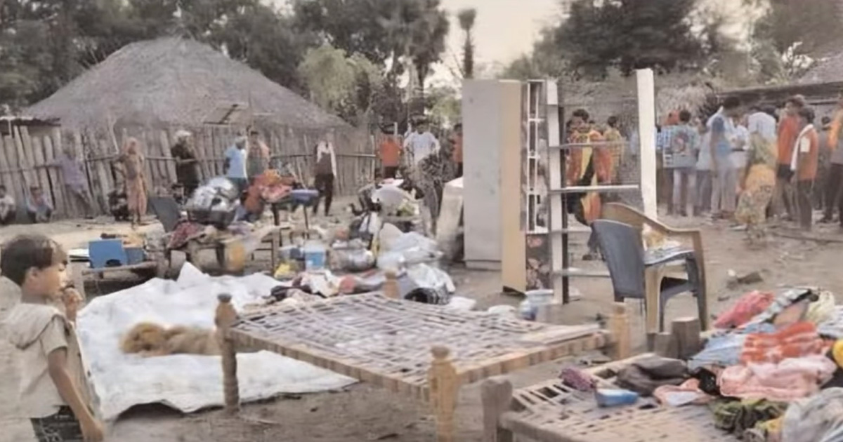 Furniture and other possessions are strewn across the ground. Several people are gathered around, observing the mess.