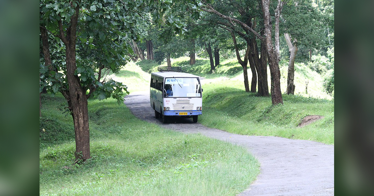 A bus is travelling down a narrow road. A bus is travelling down a narrow road.