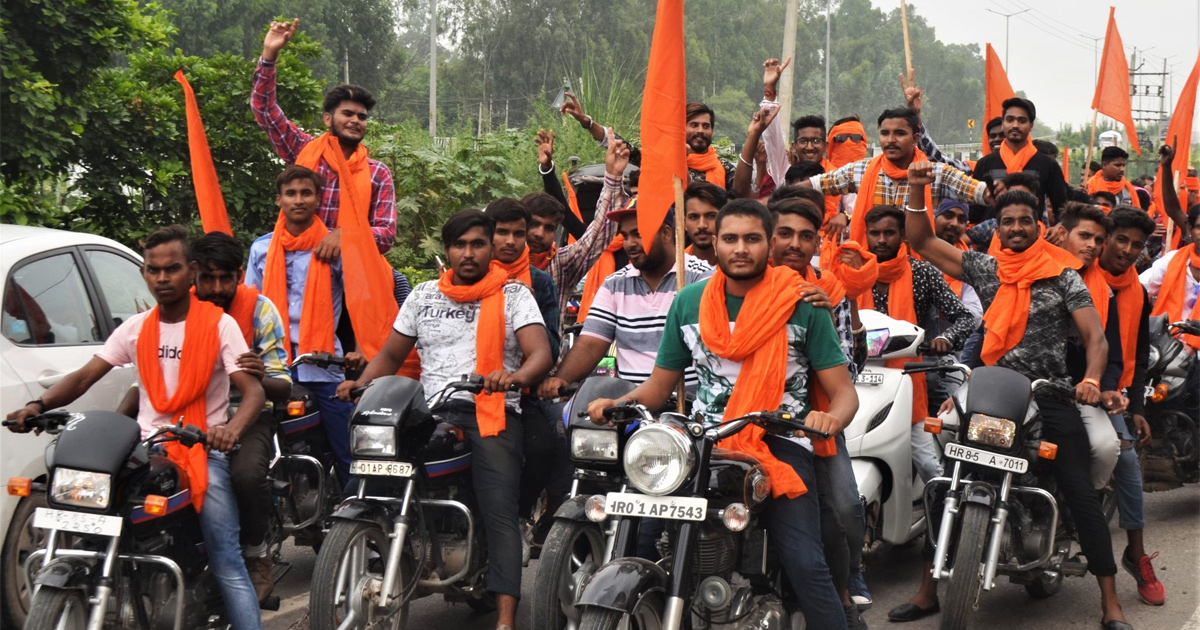 A group of people riding motorbikes, all wearing orange scarves, some carrying orange flags A group of people riding motorbikes, all wearing orange scarves, some carrying orange flags