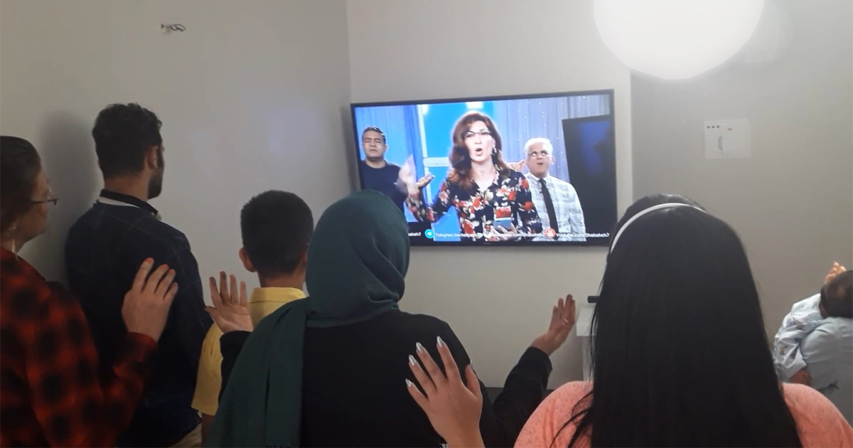 A house church is holding a service being led by a television program.