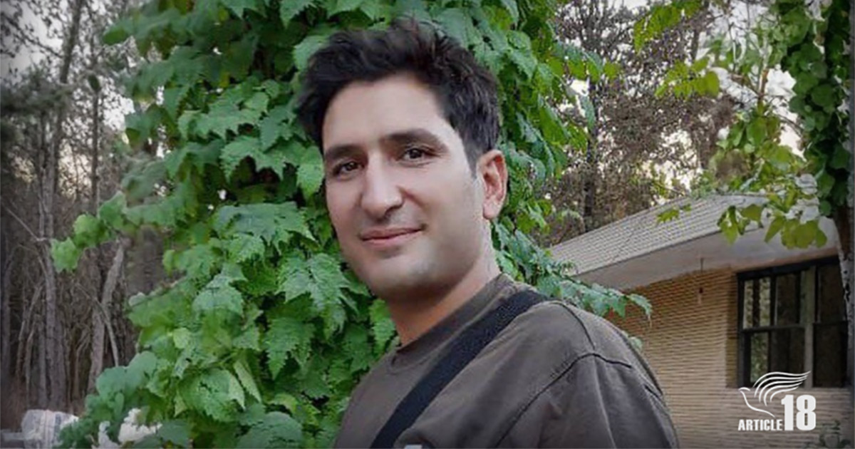 A smiling Morteza is standing outside, surrounded by trees.