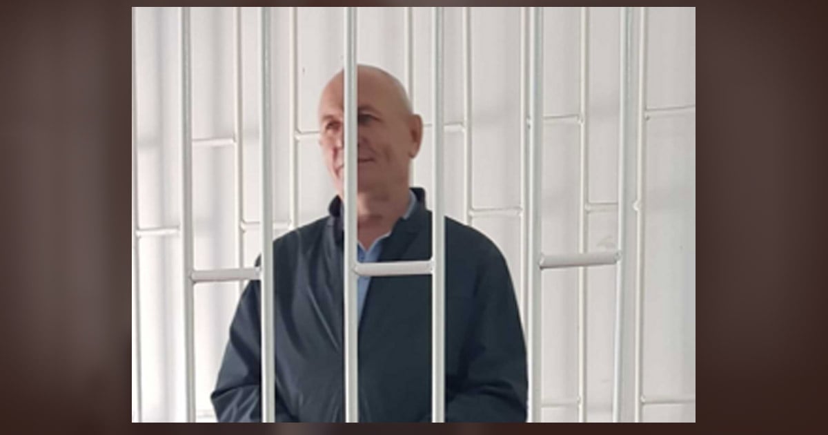 Pastor Pavel Shreider is slightly smiling as he looks through white prison bars.