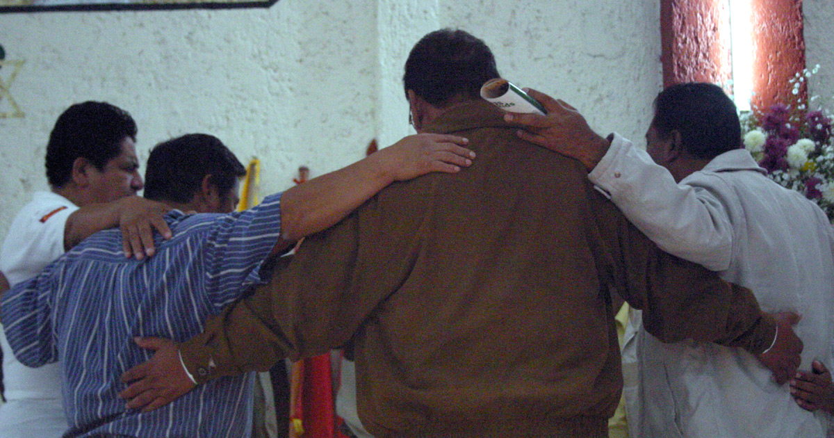 A group of men praying, arms wrapped around each other A group of men praying, arms wrapped around each other