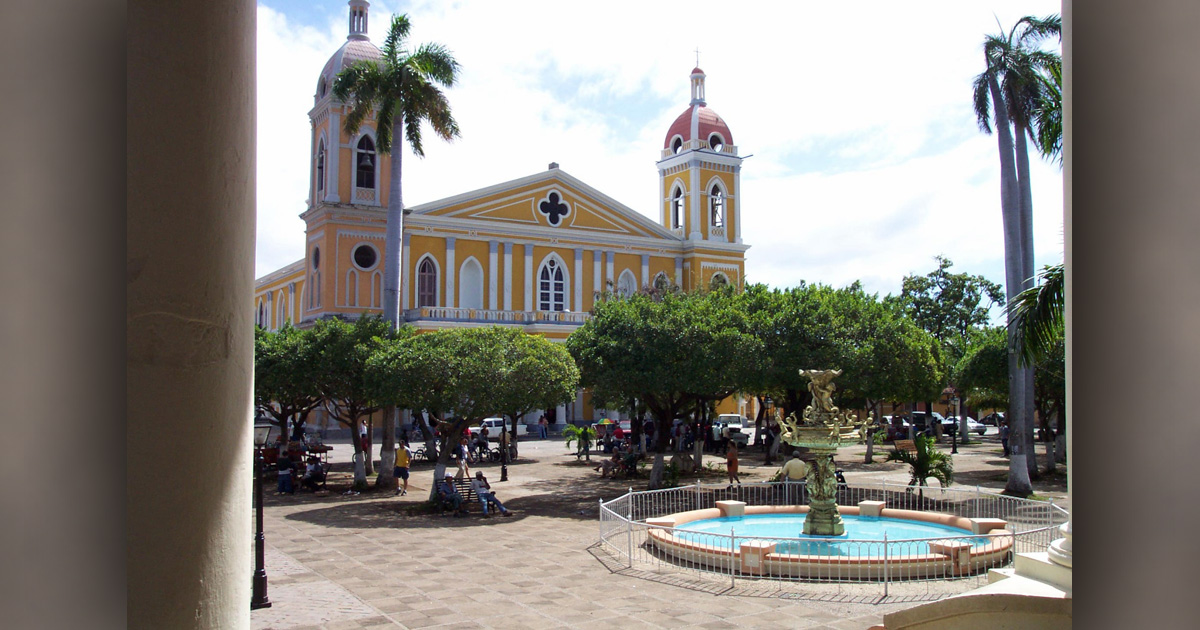 A large church is surrounded by trees. A fountain with a pond is in the foreground. A large church is surrounded by trees. A fountain with a pond is in the foreground.