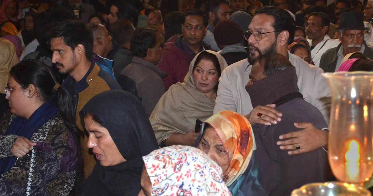 Mourners are gathered in a crowded building. Mourners are gathered in a crowded building.