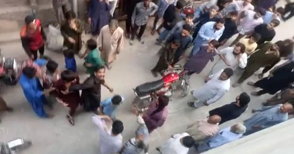 People standing outside; a motorcycle is in the middle.