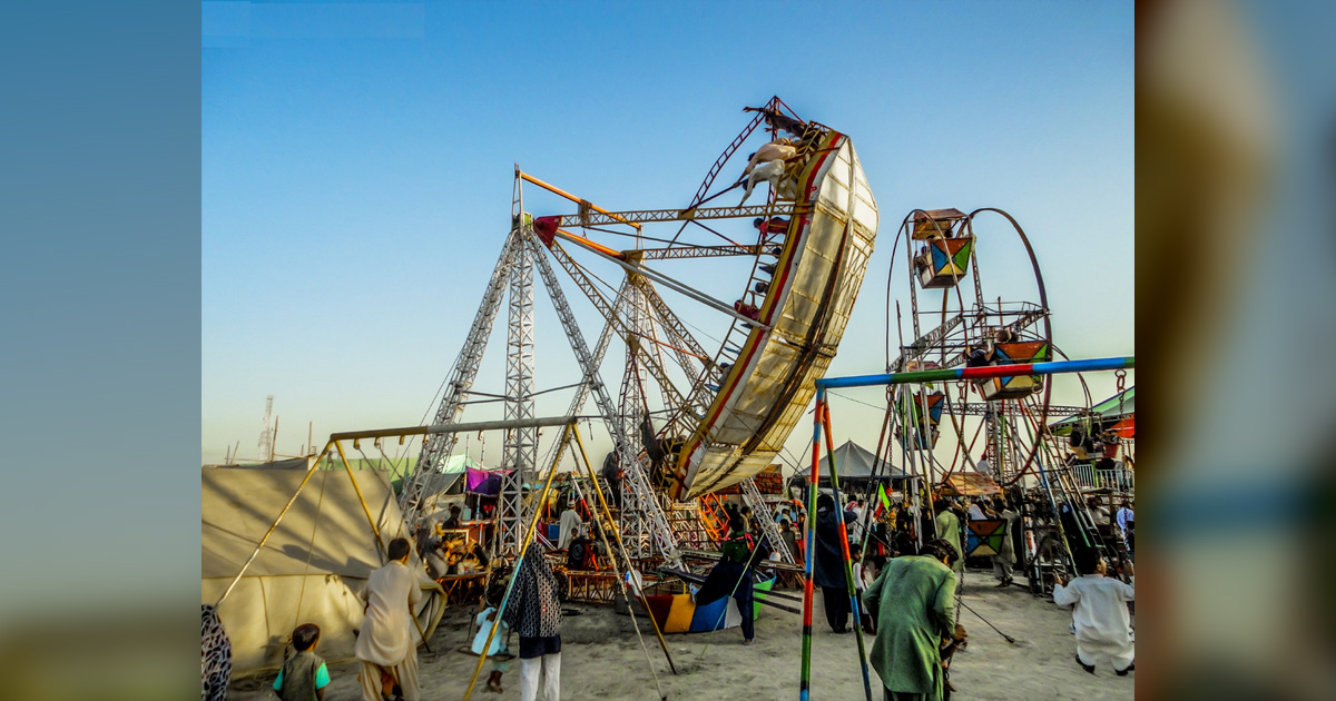 A large group of people is enjoying rides at a carnival.