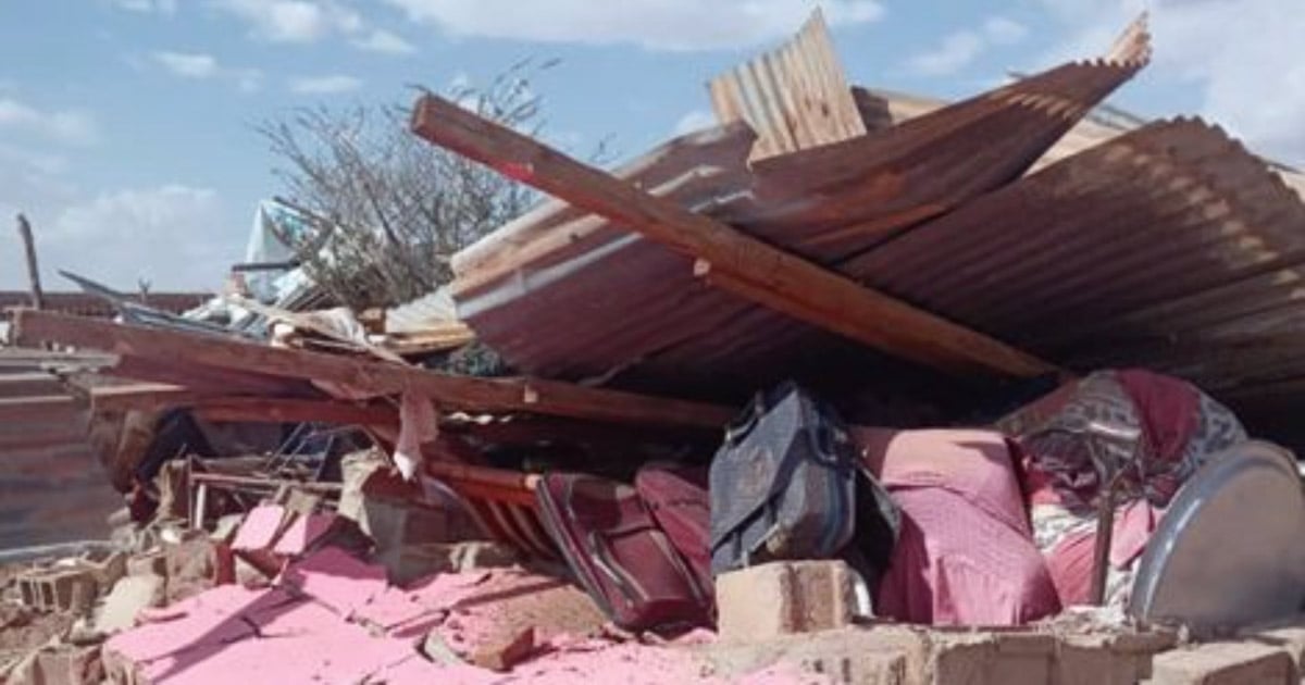 A pile of rubble - corregated metal, wood, and various other objects - is heaped where a building once stood.