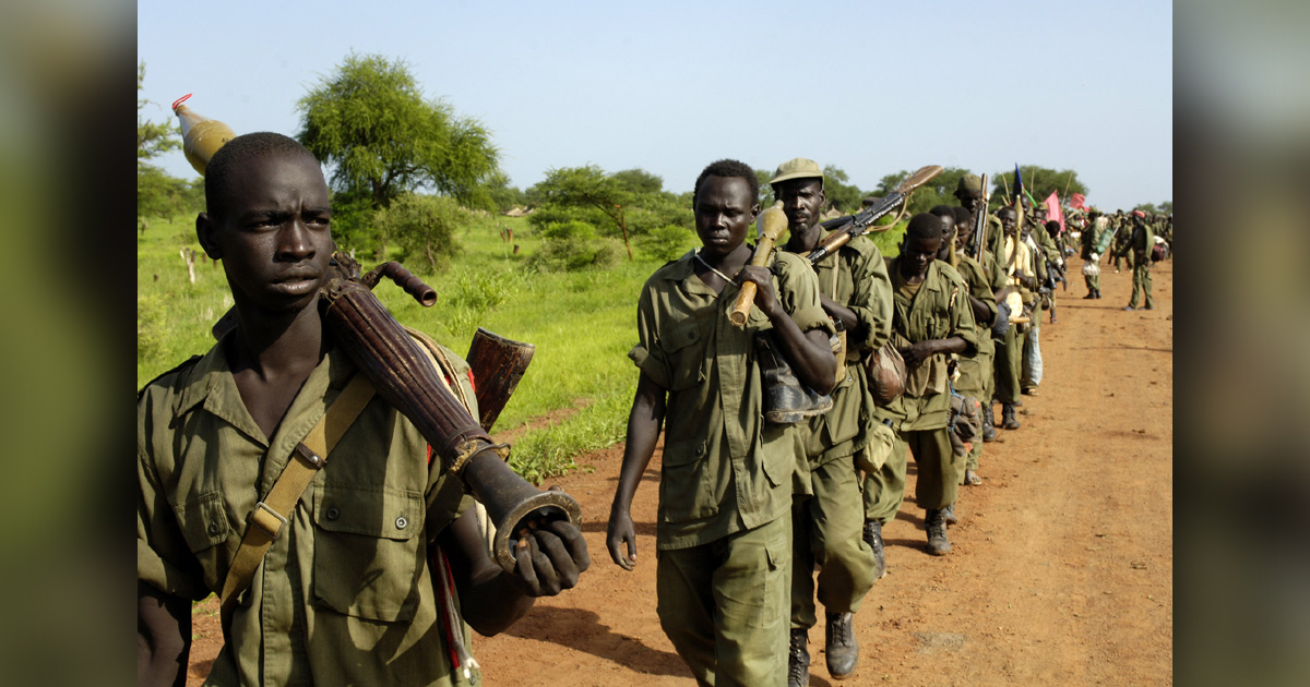 Soldiers are walking down a dirt road.