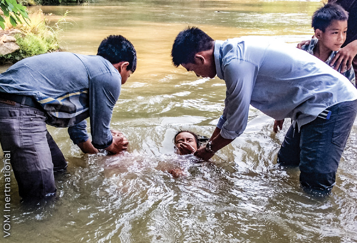 A person is being baptized by two others.
