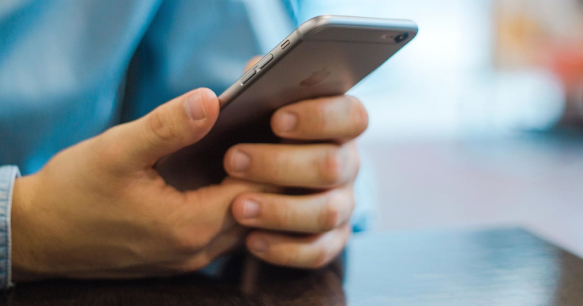 A man's hands can be seen holding a cell phone.