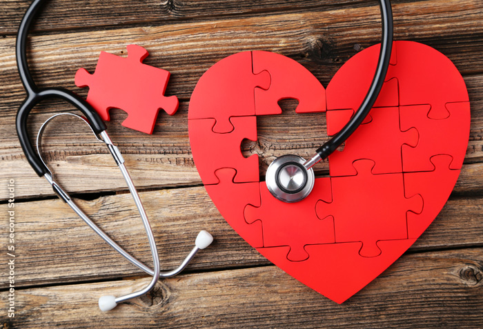 A red heart-shaped puzzle has one piece missing. A stethoscope is arranged over the puzzle. A red heart-shaped puzzle has one piece missing. A stethoscope is arranged over the puzzle.
