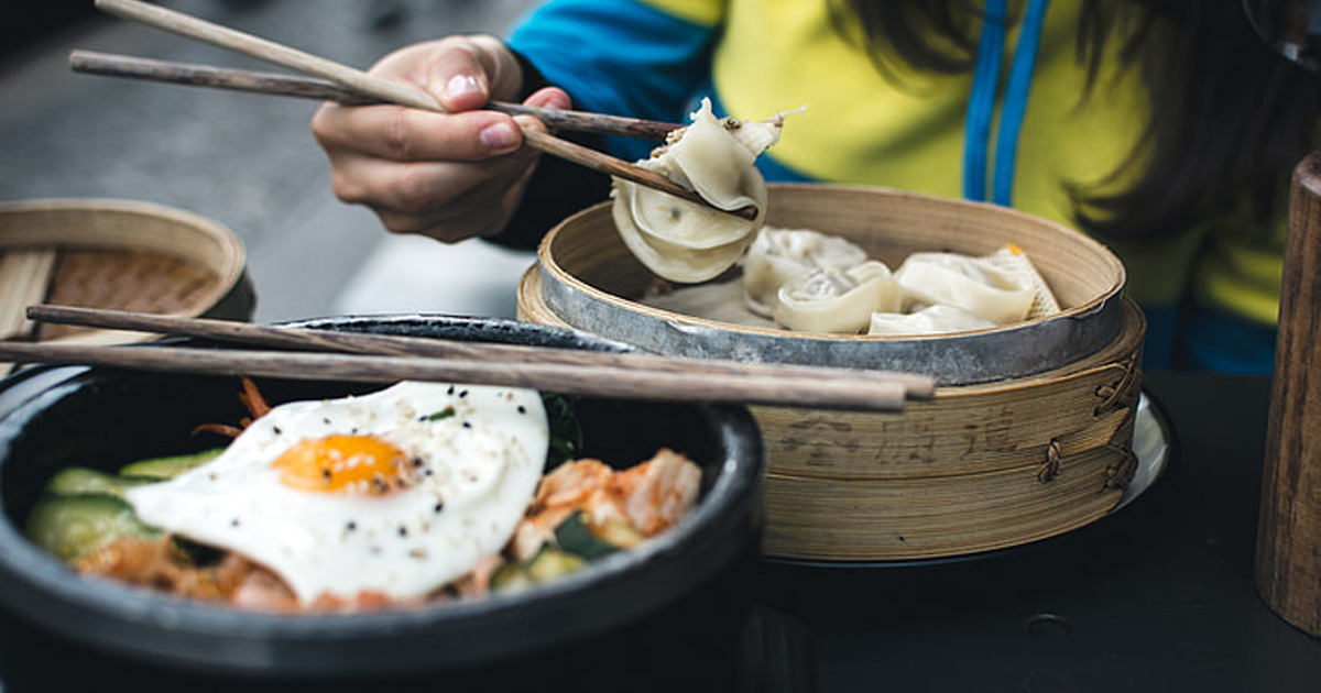 Food is placed in front of a person eating with chopsticks. Food is placed in front of a person eating with chopsticks.