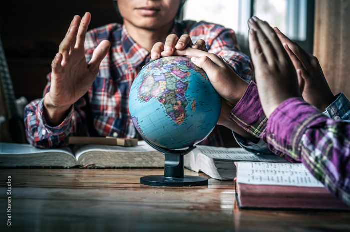 Two people praying over a globe Two people praying over a globe