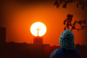 A woman looking at a cross on a church.