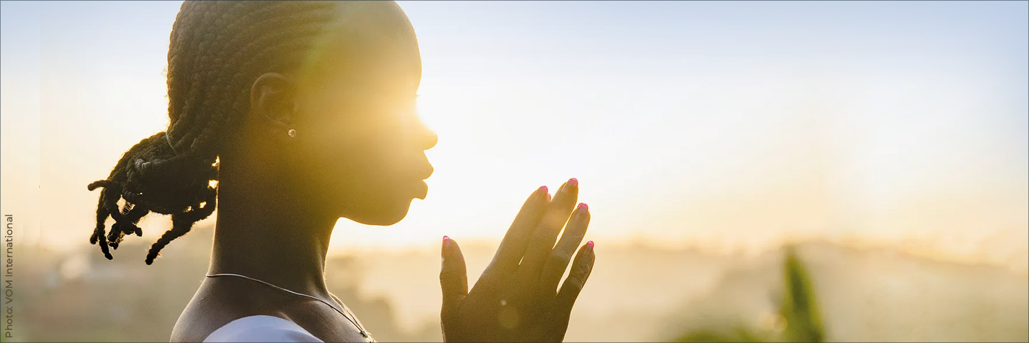 The sun creates a striking silhouette of a women in prayer. The sun creates a striking silhouette of a women in prayer.